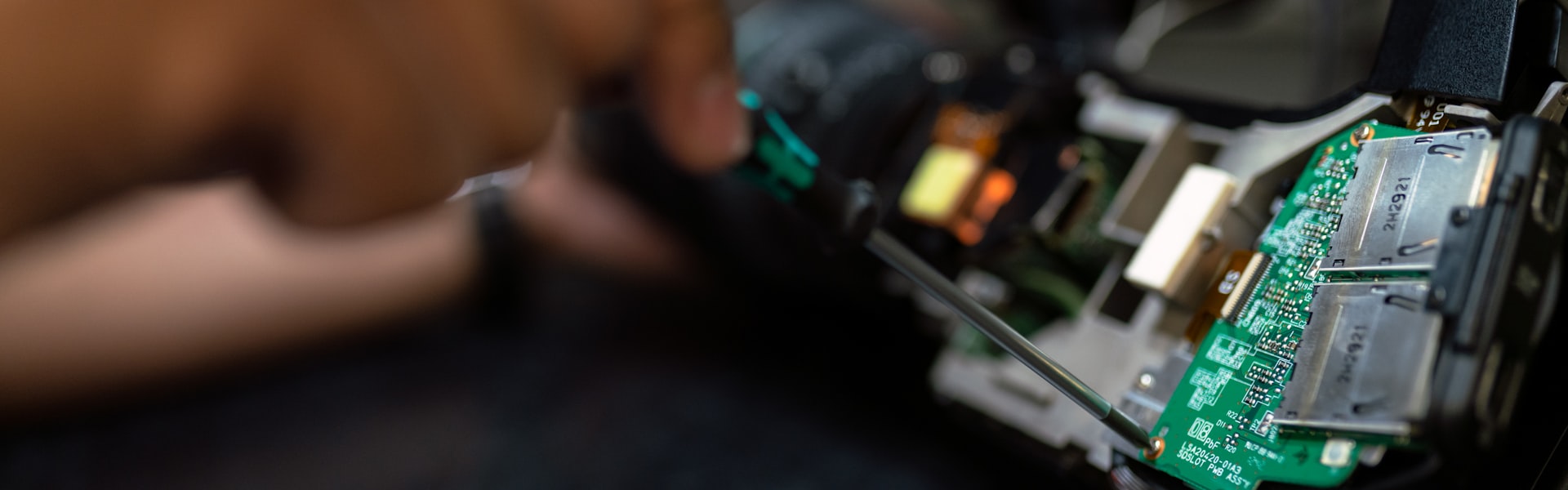Close-up of a technician's hand working on a circuit board
